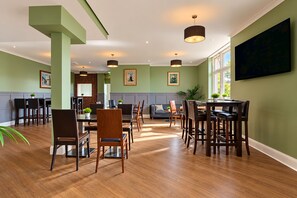 A spacious dining area with a high ceiling, wooden flooring, and modern furniture. - Belvilla Crewe Arms Hotel (Crewe)