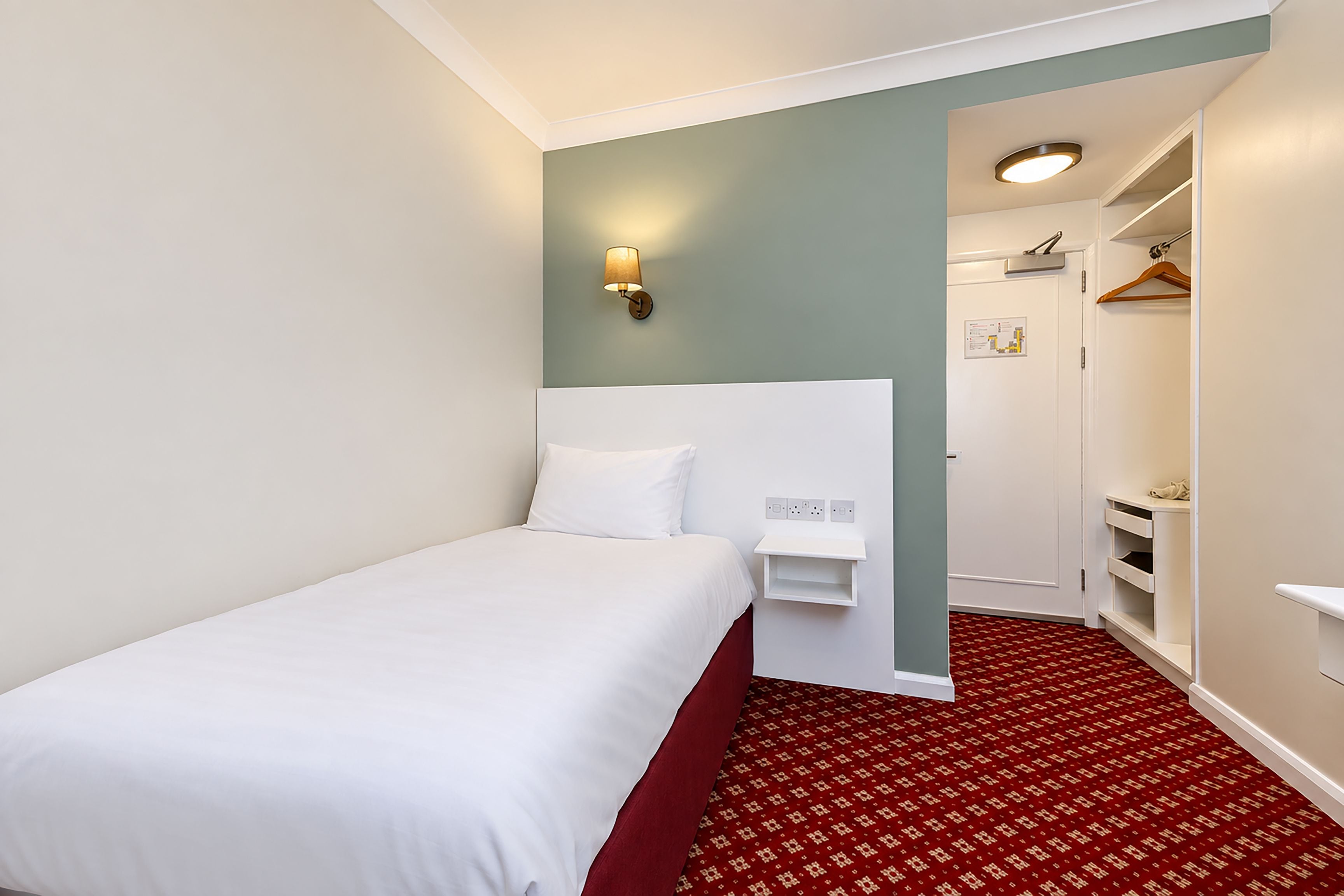 Una habitación de hotel con cama, armario y espejo.