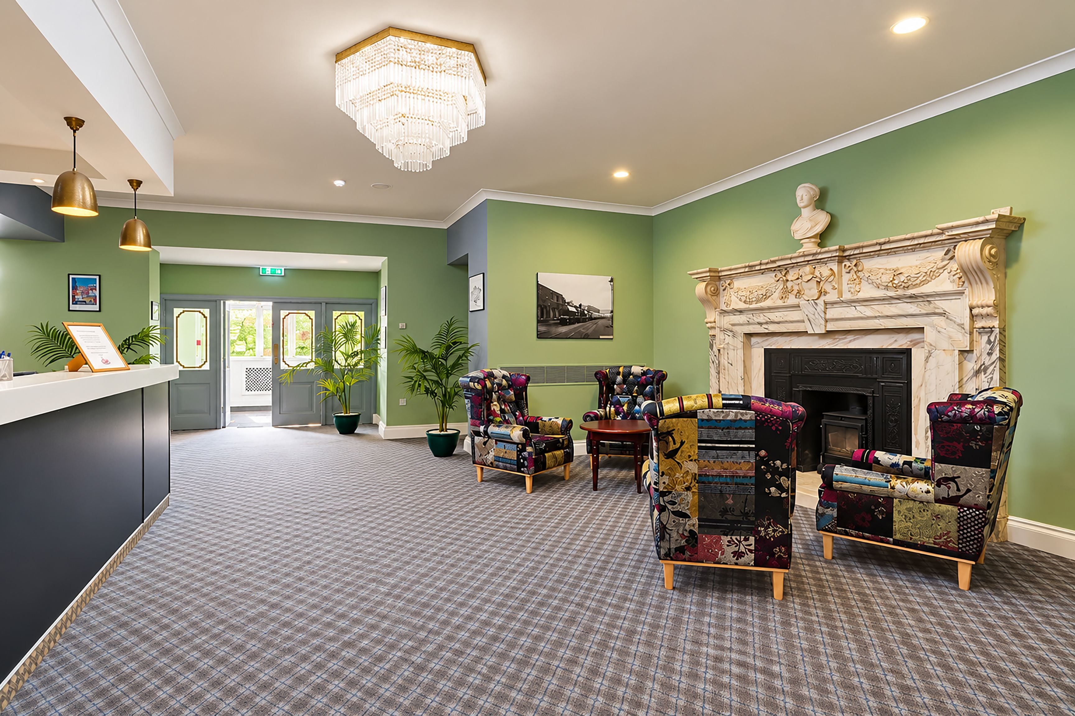 A hotel lobby with a reception desk, seating area, and a fireplace.