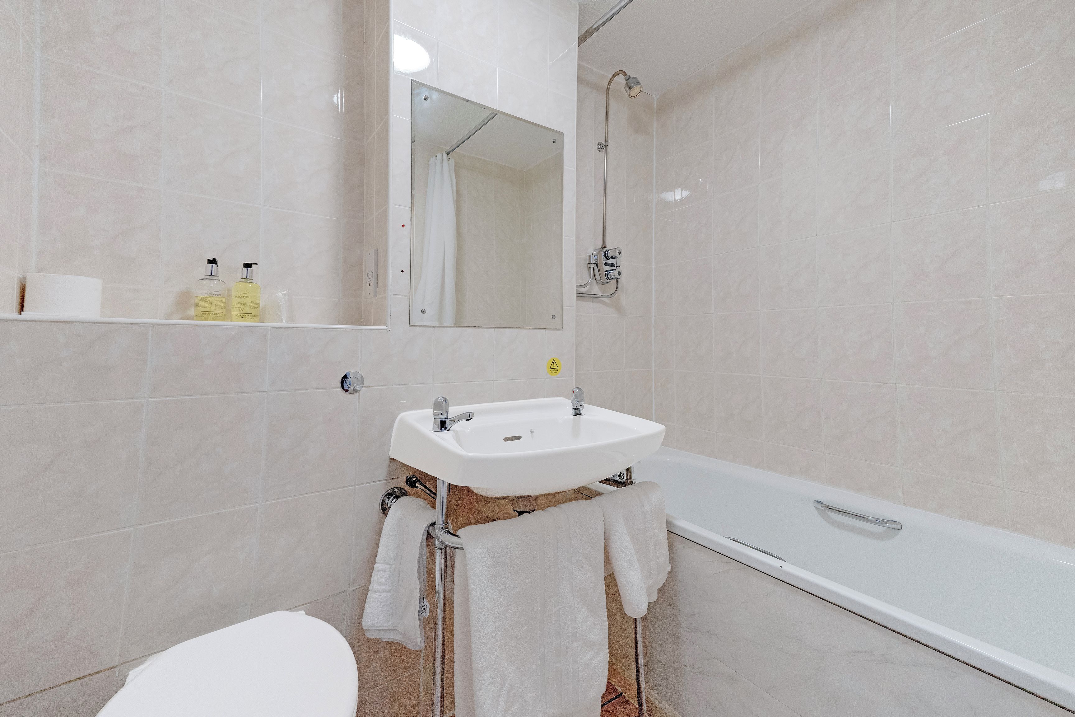 Un baño con lavamanos, espejo, ducha e inodoro.