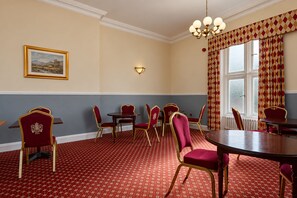 A room with a red patterned carpet, a round table, and red upholstered chairs with gold trim. - Belvilla Crewe Arms Hotel (Crewe)