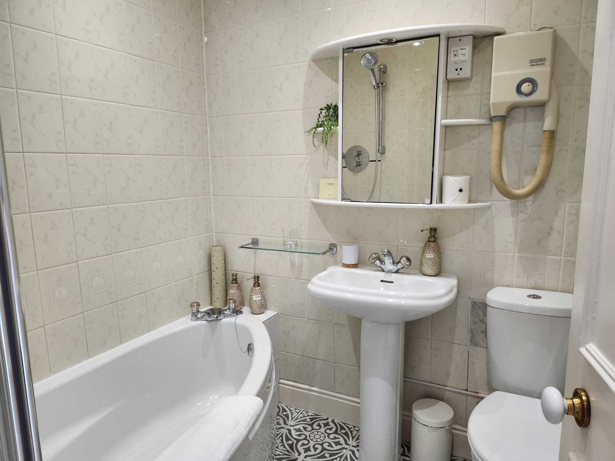 A bathroom with a bathtub, a pedestal sink, and a toilet.