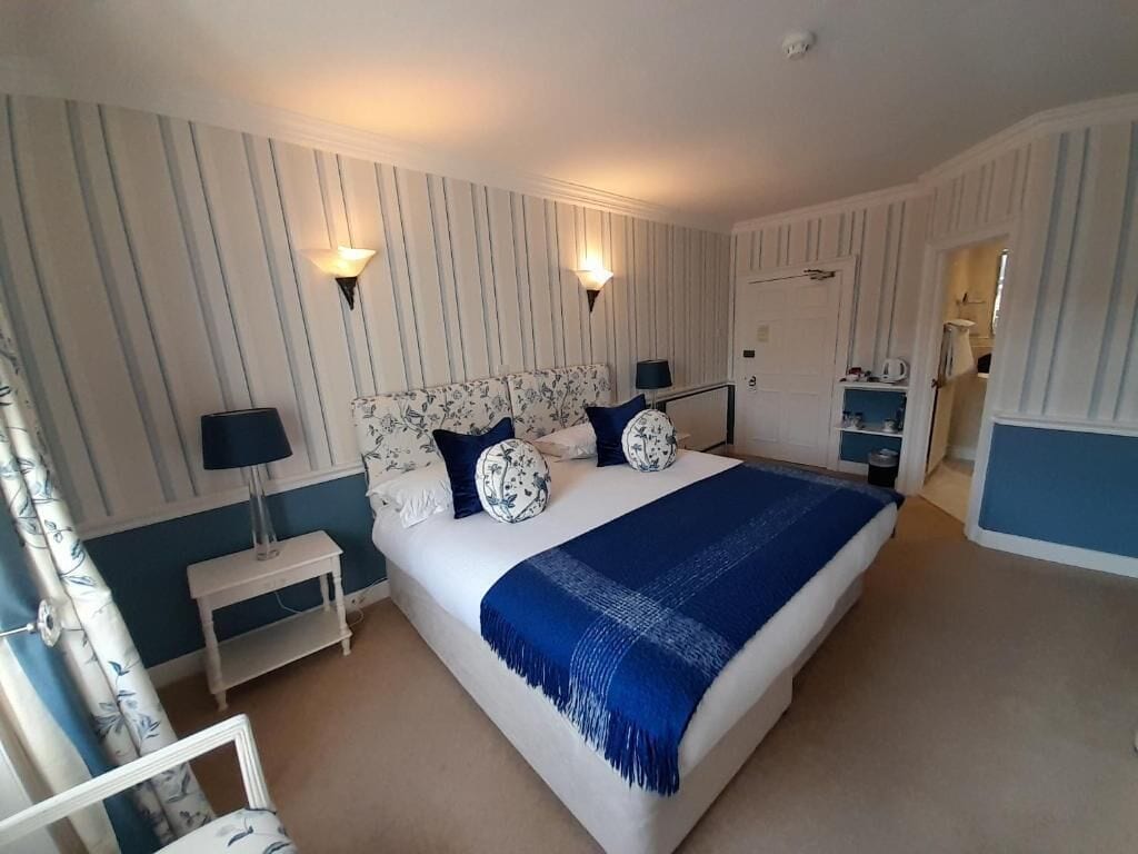 A bedroom with a large bed, two bedside lamps, a nightstand, and a dresser.