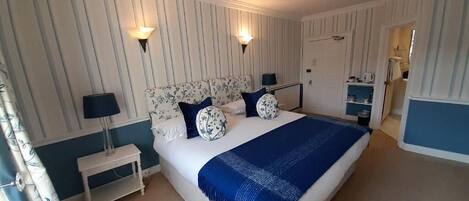 A bedroom with a large bed, two bedside lamps, a nightstand, and a dresser.