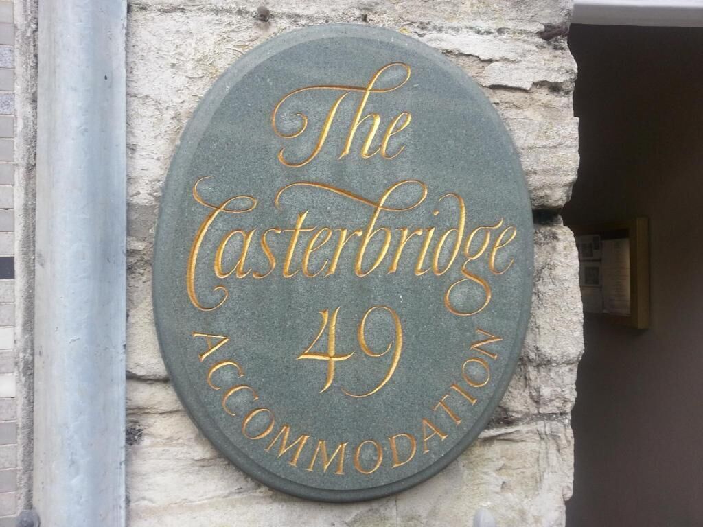 A circular sign with "The Easterbridge 49 Accommodation" written on it, mounted on a stone wall.