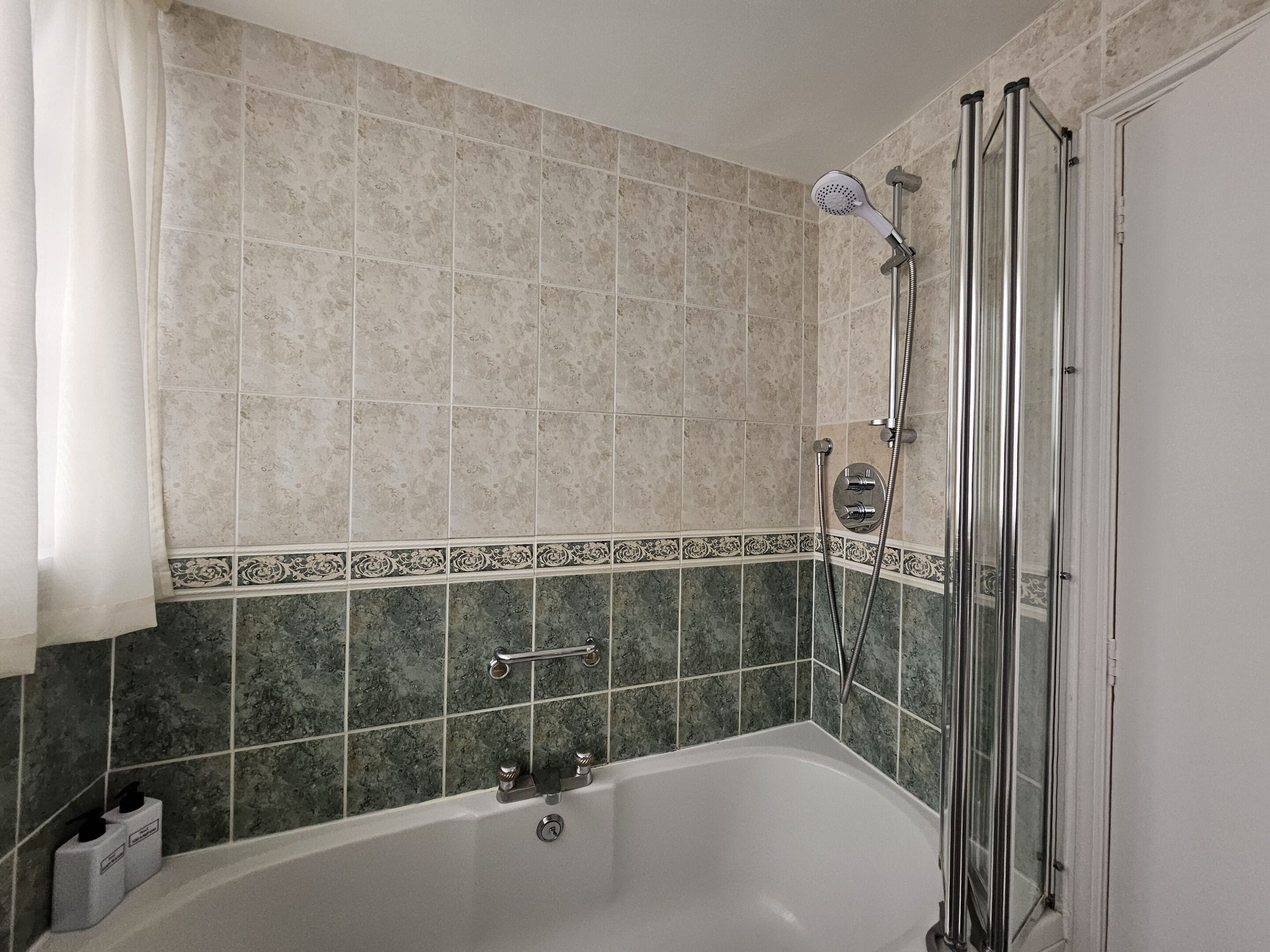 A bathroom with a bathtub, shower, and tiled walls.