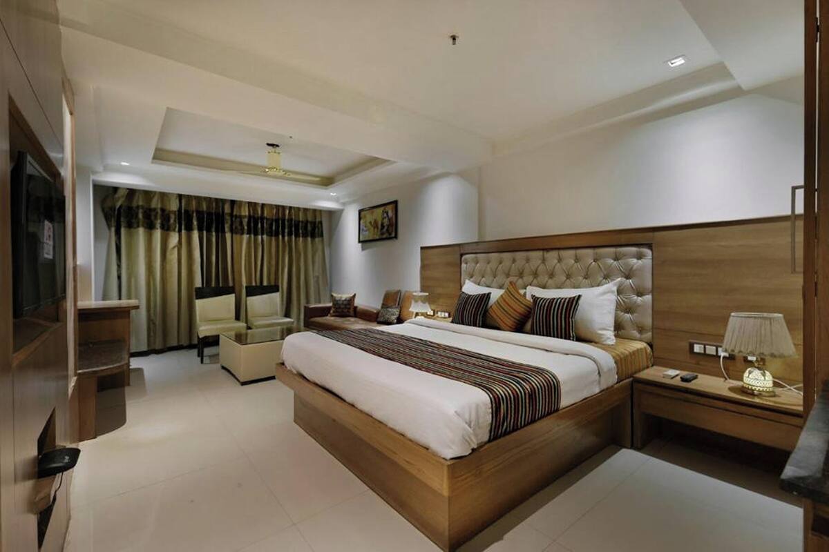 A spacious bedroom with a large bed, a nightstand, a chair, and a television.