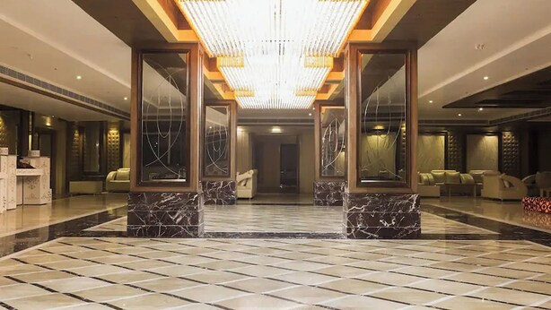 A spacious lobby with a high ceiling, marble flooring, and a central chandelier. - Hotel Lotus Paradise (Sonepat)