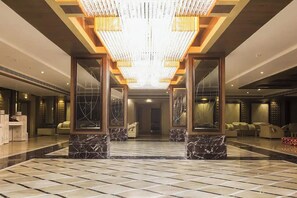 A spacious lobby with a high ceiling, marble flooring, and a central chandelier. - Hotel Lotus Paradise (Sonepat)