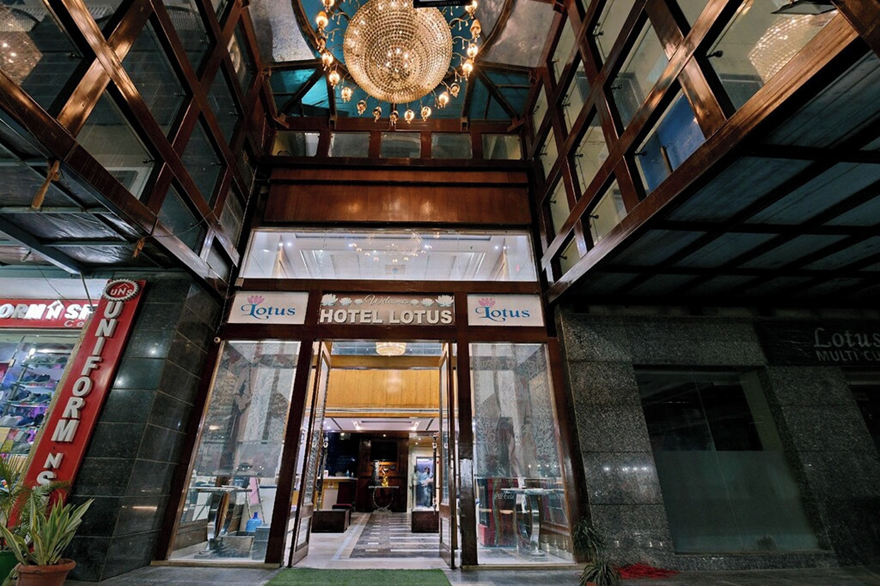 The entrance to Hotel Lotus with a grand chandelier, glass doors, and a visible interior pathway leading inside.
