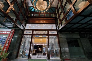 The entrance to Hotel Lotus with a grand chandelier, glass doors, and a visible interior pathway leading inside. - Hotel Lotus Paradise (Sonepat)