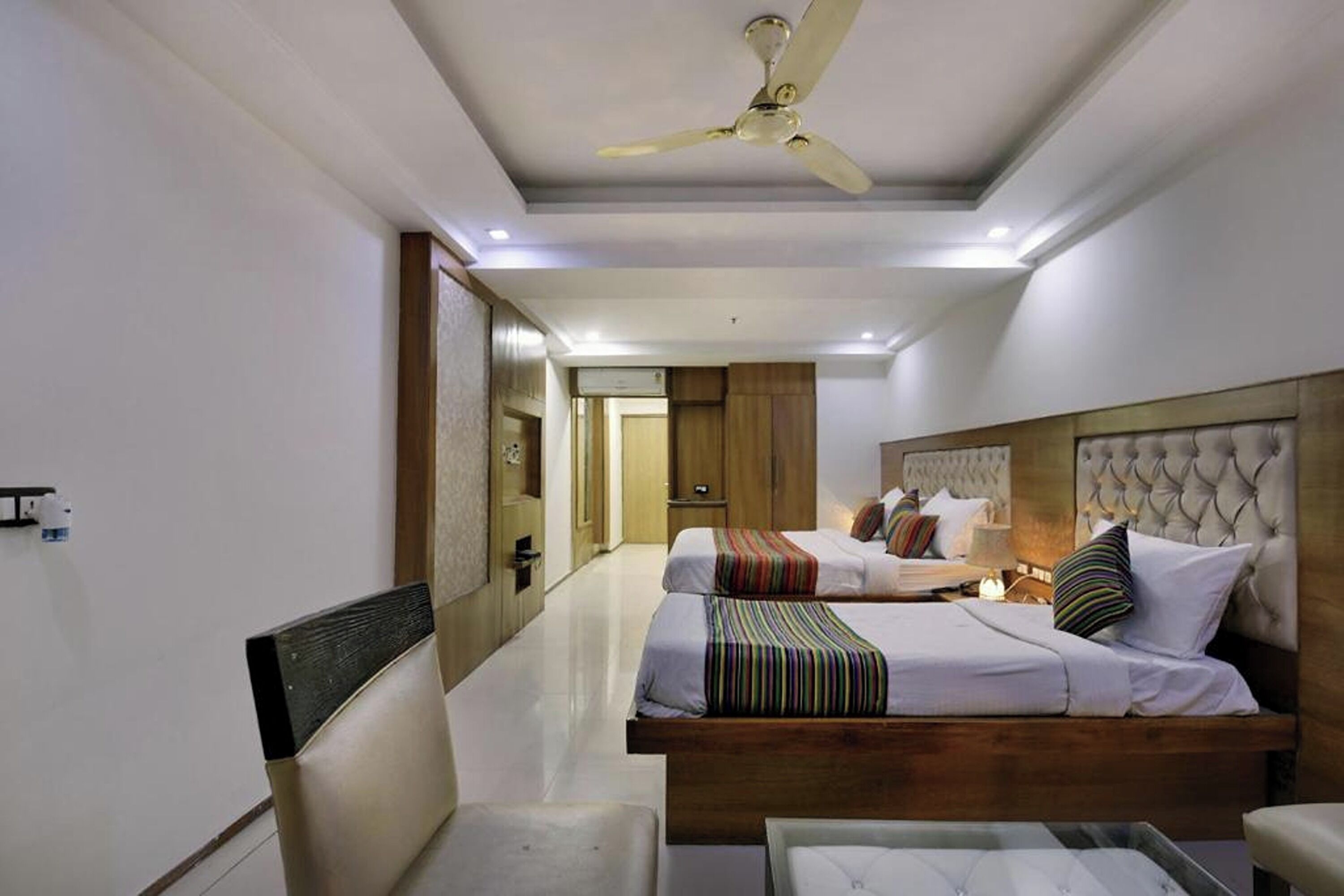 Une chambre d’hôtel avec deux lits, un ventilateur de plafond et un design moderne.