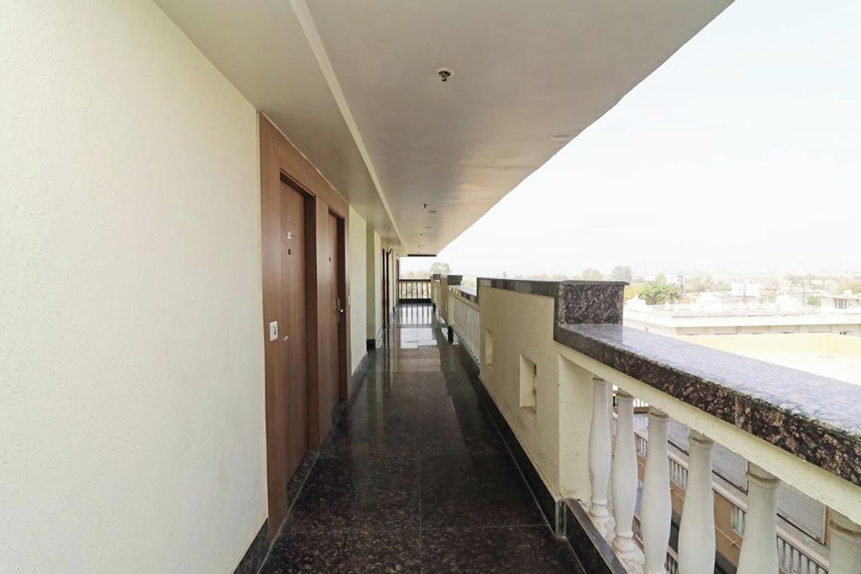 Un pasillo con piso de mármol que conduce a un balcón con vistas a edificios.