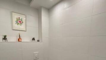 Un bagno piccolo con il water, un lavandino e uno scaffale con un quadro incorniciato e una bottiglia.