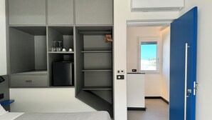 A modern hotel room with a large wardrobe, a bed, a small kitchenette, and a view of the outside. - A&A Rooms (Anacapri)