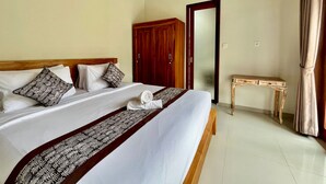 A hotel room with a large bed, wooden headboard, a desk, and a wardrobe. - Belvilla Pantai Senja Resort Central Ubud (Pecatu)