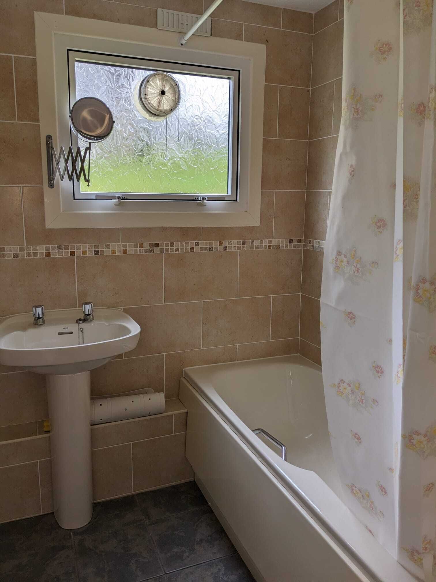 A bathroom with a window, a sink, and a bathtub.