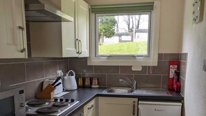 Une cuisine de taille réduite équipée d’une cuisinière, d’un four, d’un évier et d’un petit réfrigérateur.