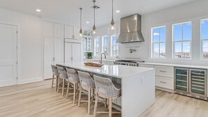 A modern kitchen with a large island, pendant lights, and a view of the city. - Pet-Friendly Home@Cinnamon Shore South w/ Gulf View & Extras Galore! (Port Aransas)