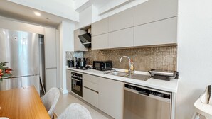 Ett modernt kök med vitvaror i rostfritt stål, kakel ovanför arbetsbänken och en diskmaskin.
