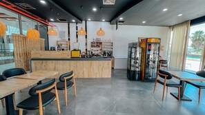 A modern cafe with a wooden counter, black chairs, and pendant lighting.