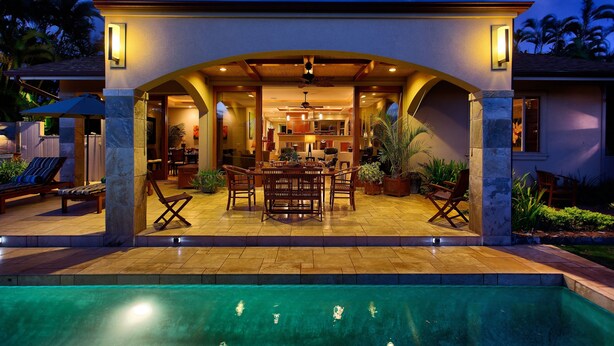 Eine Poolterrasse mit Essbereich, Deckenventilator und Blick ins Hausinnere.