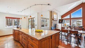 Una cocina amplia con una isla grande, armarios de madera e iluminación colgante.