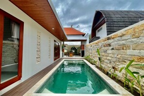 A modern house with a swimming pool, stone walls, and wooden beams. - Belvilla Tirta Sari Resort Central Ubud (Ubud)