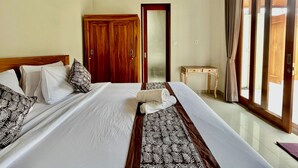 A hotel room with a large bed, wooden ceiling, a wooden door, a small table, and a large window with curtains. - Belvilla Tirta Sari Resort Central Ubud (Ubud)