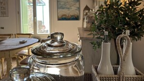 Une cuisine avec une table à manger, une lampe et un panier en osier contenant des bocaux et des vases.