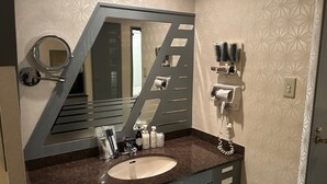 A bathroom with a large mirror, a sink, and a towel dispenser.