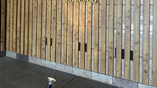 A reception area with a wooden slat wall and a sign that reads "HOTEL STAY KAWASAKI".