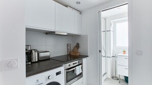 A compact kitchen with a washing machine, oven, and toaster.