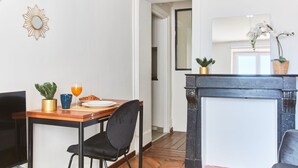 A dining area with a wooden table, black chairs, a TV, and a fireplace.