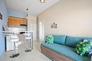 A modern kitchen with wooden cabinets, a white countertop, and two white bar stools. - Sun Beach Apartments in Chania 8 & 10 & 13 (Chania)