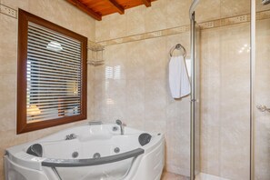 Une salle de bain avec une baignoire sur pieds, une douche à parois de verre et un porte-serviettes.