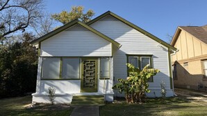 A single-story house with a front porch, a garage, and a small front yard with a tree and a plant. - Gathering Place On Columbus Sleeps 8 (Waco)