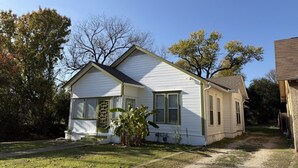 A single-story house with a front porch, a small garden, and a clear sky. - Gathering Place On Columbus Sleeps 8 (Waco)
