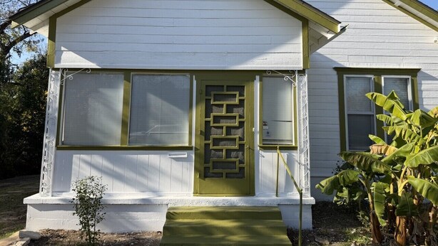 A white house with a green door, large windows, and a small porch. - Gathering Place On Columbus Sleeps 8 (Waco)