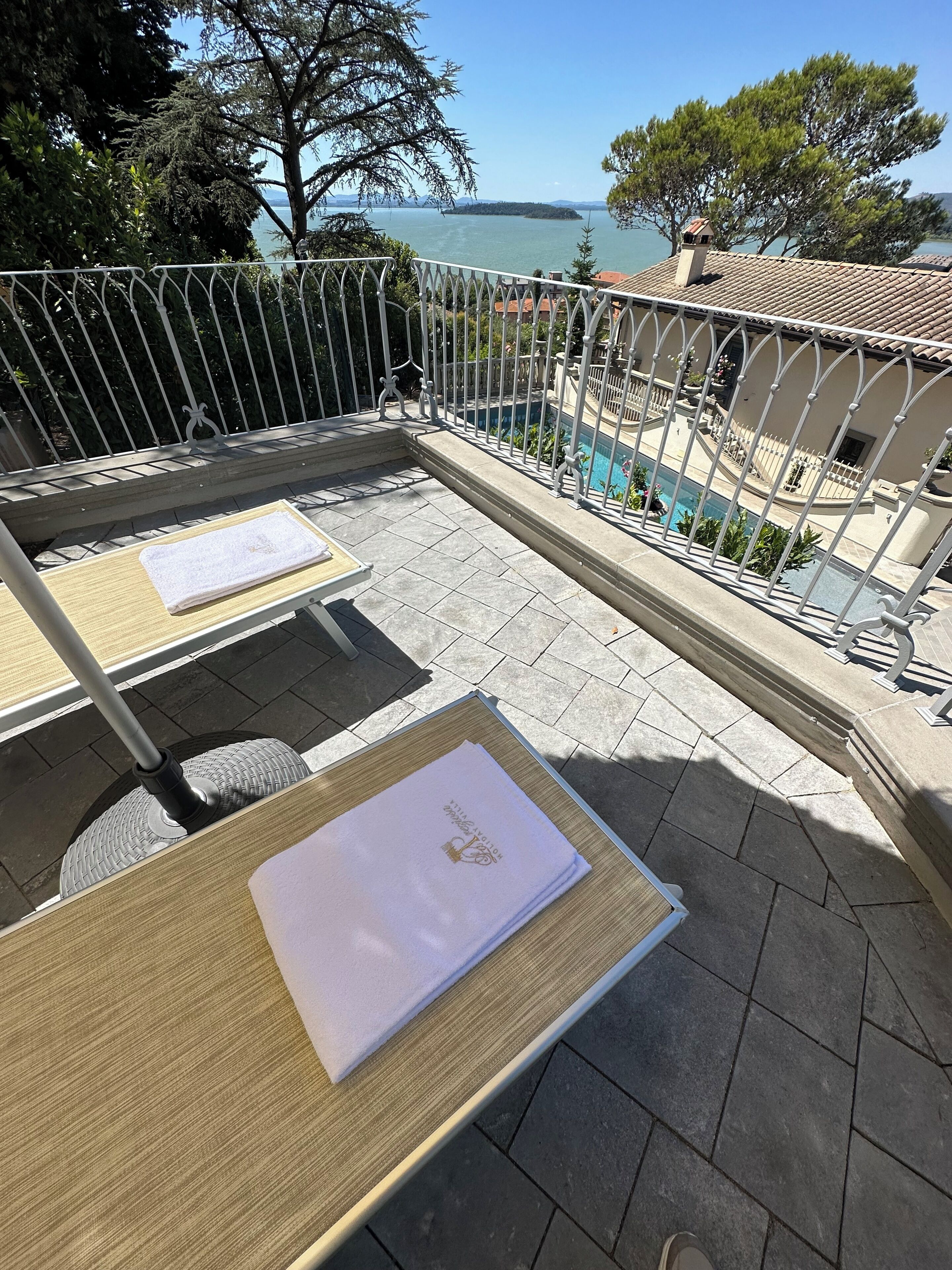 An outdoor terrace with two sun loungers, a pool, and a view of the sea.