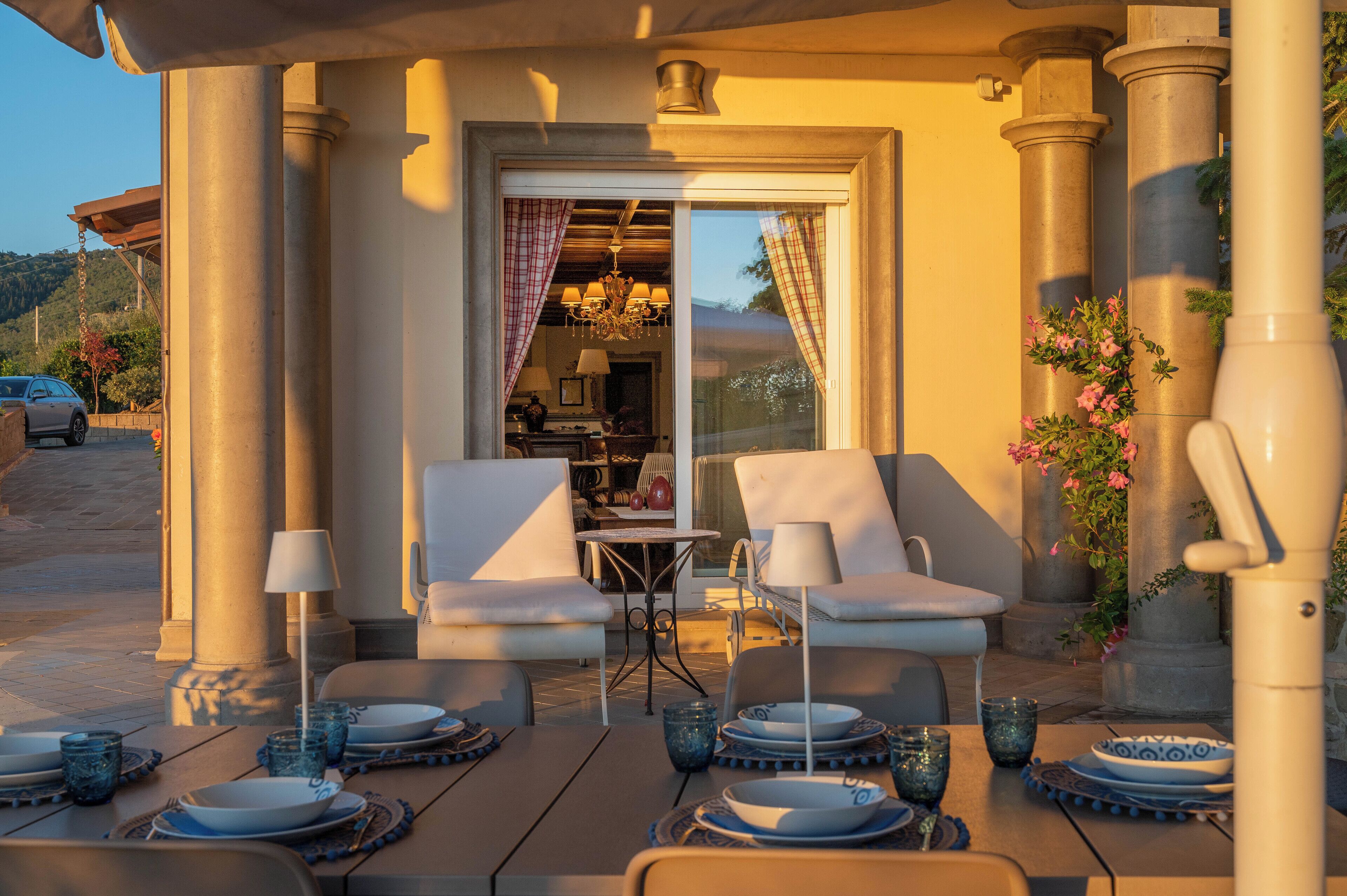 An outdoor dining area with two white chairs, a table, and blue plates and glasses.