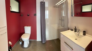 Une petite salle de bain comprenant des toilettes, une douche et un lavabo.
