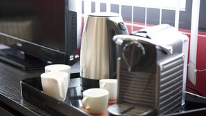 Un plateau contenant une machine à café, quatre tasses blanches et un petit appareil, probablement un appareil pour maintenir les aliments au chaud, est posé sur un plan de travail foncé.