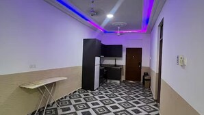 A narrow hallway with a patterned floor, a small ironing board, a black cabinet, and a ceiling fan. - 5 Bedroom House Sleeps 12 -balcony -hired Security (Tema)