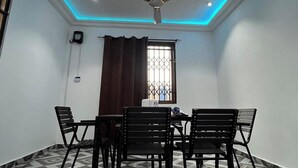 A conference room with a ceiling fan, a window with bars, a table with chairs, and a patterned floor. - 5 Bedroom House Sleeps 12 -balcony -hired Security (Tema)