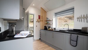 Una cocina moderna con armarios grises, encimera negra y ventana con vistas al exterior.