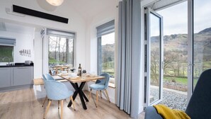 Una cocina moderna con comedor, ventanas amplias y vista al campo.