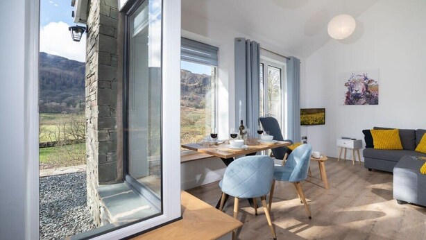 Una sala de estar moderna con comedor, ventanas amplias y vistas al exterior.