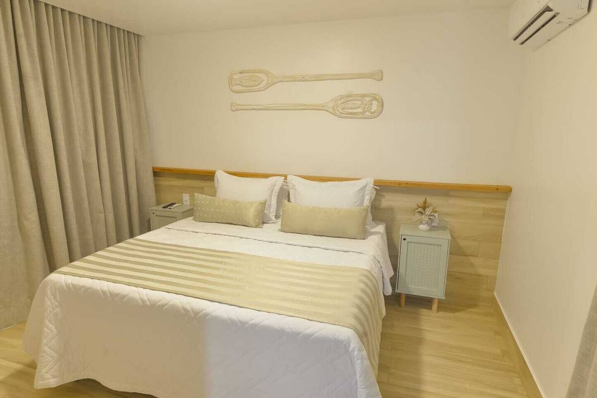 A neatly arranged bedroom with a bed, pillows, a nightstand, and a wall-mounted key.