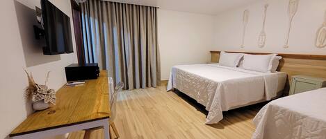 A hotel room with two beds, a desk, a flat-screen TV, and a wall-mounted air conditioner.